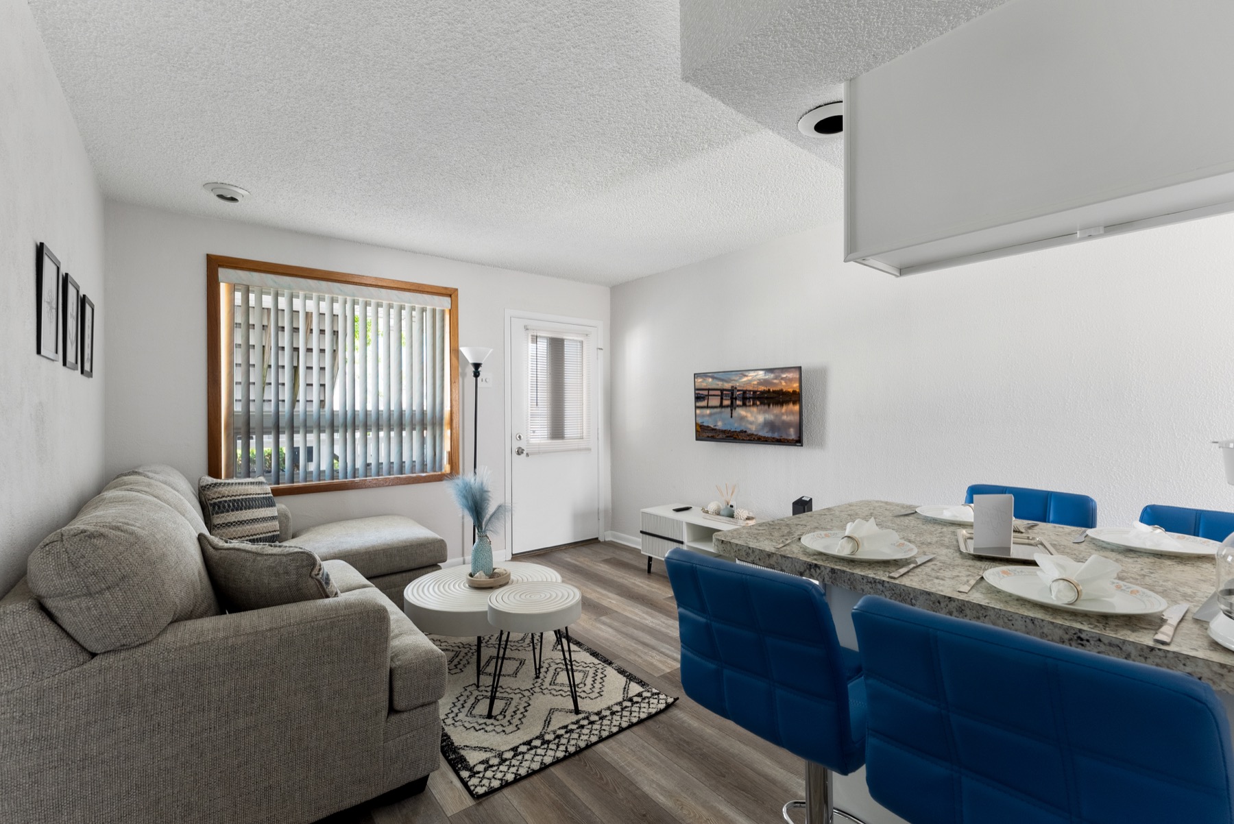 Living and dining area with sofa, TV, and blue counter seats